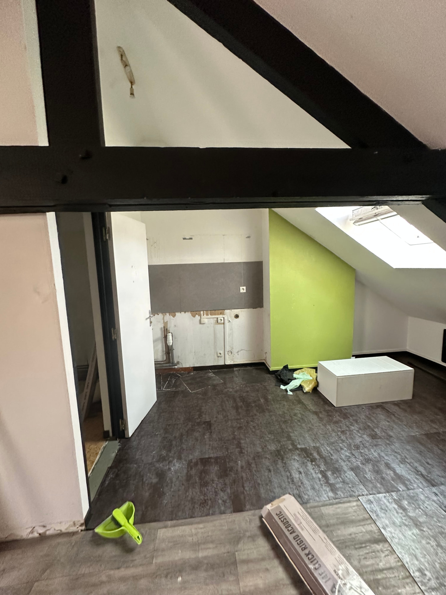 Combles avant travaux avec cloison verte et sol abîmé